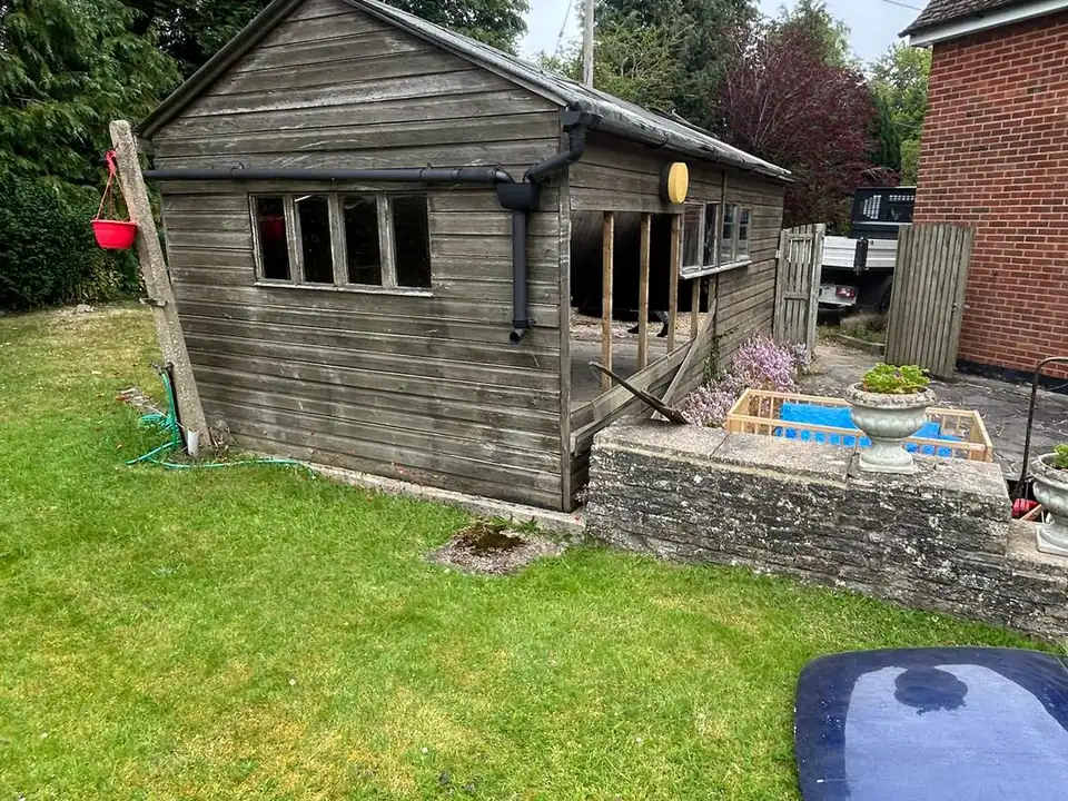 An old timber garage on a lawn before Excel removed it